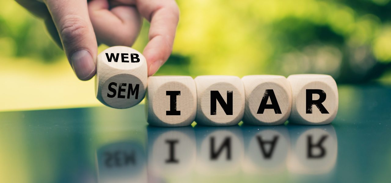 Modern Webinar or traditional Seminar? Hand turns a cube and changes the word “seminar” to “webinar”.
